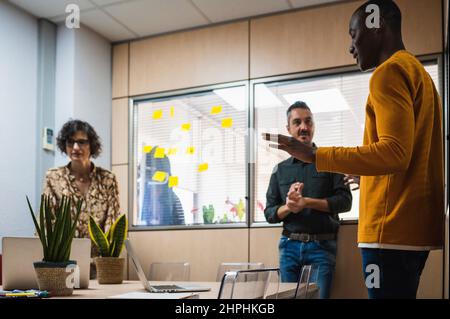 Ein vielseitiges Arbeitsteam, das in einem Besprechungsraum spricht. Stockfoto