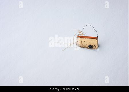 Willkommensschild umgeben und in einer frischen, sauberen, weißen Schneedecke versunken. Das bemalte Holzschild hat einen Drahtgriff. Es ist Platz für Textnachrichten verfügbar. Stockfoto