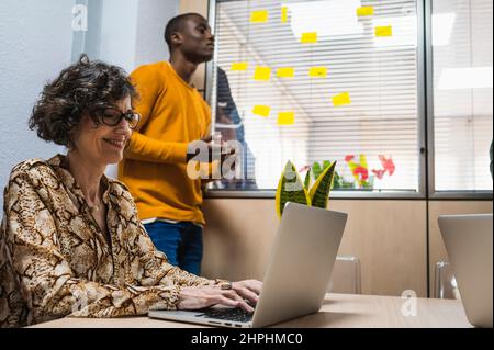 Ältere Frau und schwarzer junger Mann, der ein Projekt in einem Büro vorbereitet. Stockfoto