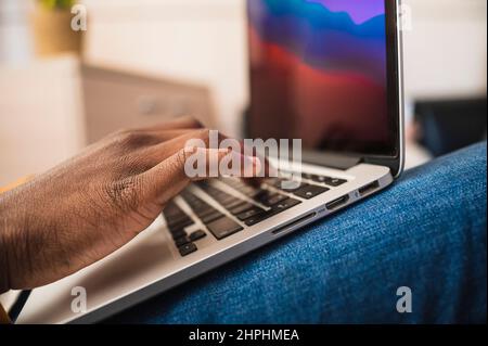 Nahaufnahme der Hände eines schwarzen Mannes, der in einem Büro auf einem Laptop tippt. Stockfoto