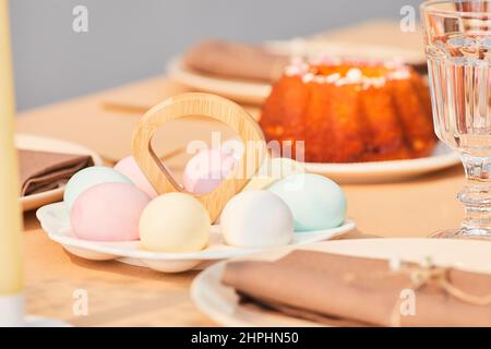 Nahaufnahme von pastellfarbenen Ostereiern auf einem eleganten Esstisch, der für den Frühling dekoriert ist, Platz zum Kopieren Stockfoto