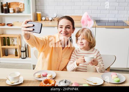 Portrait der glücklichen Mutter, die Selfie mit niedlichen Sohn in hellen Küche Innenraum, kopieren Raum Stockfoto