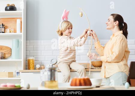 Seitenansicht Porträt einer jungen Frau Dekoration Haus für Ostern mit niedlichen kleinen Jungen tragen Hasenohren, kopieren Raum Stockfoto