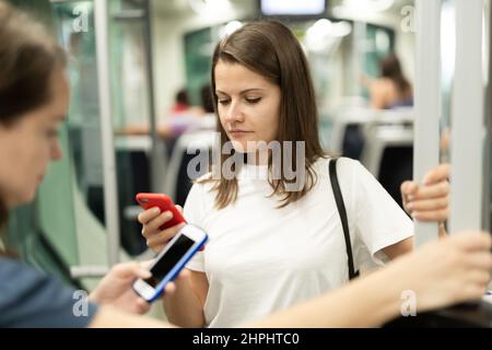 Positive Frau lesen vom Mobiltelefon in der Kabine von Bus oder Straßenbahn Stockfoto