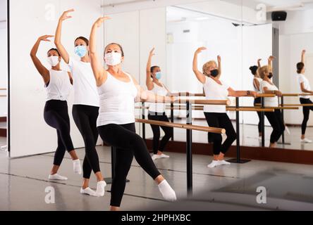 Frauen in Masken üben Ballettbewegungen im Trainingsraum Stockfoto