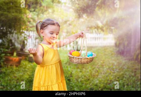 Porträt eines kleinen Mädchens mit einem Osterkorb mit Eiern im Hinterhof Stockfoto
