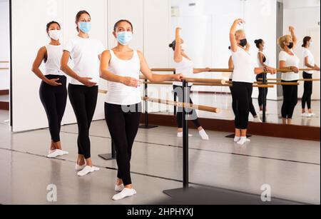 Frauen in Masken üben Ballettbewegungen im Trainingsraum Stockfoto