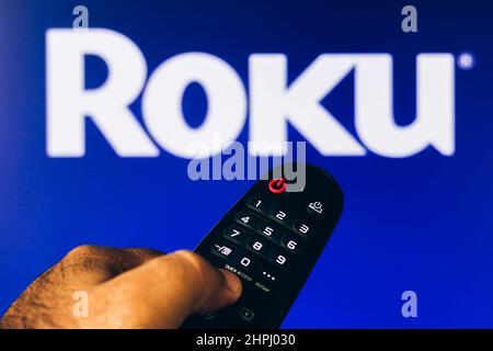 Brasilien. 21st. Februar 2022. In dieser Abbildung sehen Sie eine Nahaufnahme einer Hand, die eine TV-Fernbedienung hält, die vor dem Roku-Logo zu sehen ist. Kredit: SOPA Images Limited/Alamy Live Nachrichten Stockfoto