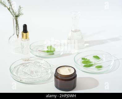 Vegane kosmetische Creme und Labor-Petrischalen auf einem Labortisch und Glaswaren. Natürliche kosmetische Inhaltsstoffe. Test Clruelty-free Gesichtspflege Feuchtigkeitscreme. Stockfoto