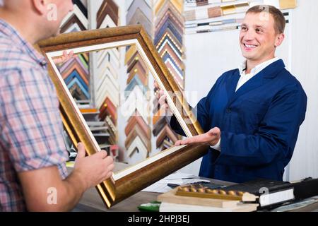 Porträt eines Verkäufers, der auf dem Bilderrahmen des Kunden am Ladentisch bestellt Stockfoto