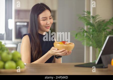 Schöne asiatische Bloggerin präsentiert ihre Zutaten für gesunde Salatschüssel auf ihrem Online-Kanal. Stockfoto