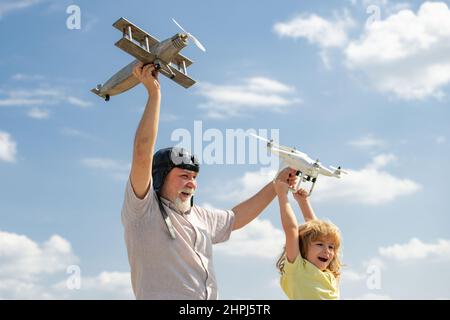 Großvater und Sohn mit Flugzeug und Quadcopter Drohne über blauem Himmel und Wolken Hintergrund. Männer Generation Großvater und Enkel. Ältere, alte Verwandte Stockfoto