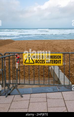 Warnschild an einer Metallbarriere, das den Zugang zu den Stränden der Atlantikküste verbietet, mit der Aufschrift „Hochwasserwellen – Zugang verboten“ in französischer Sprache Stockfoto