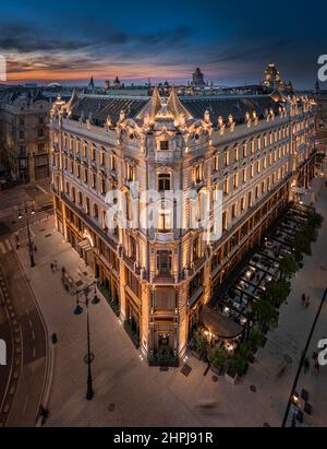 Budapest, Ungarn - Luftaufnahme eines renovierten beleuchteten Luxus-Collection-Hotels in der Nähe von Ferenciek tere nach Sonnenuntergang in der Innenstadt von Budapest mit bunten Stockfoto