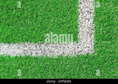 Ein Teil des Fußballfeldes aus der Nähe, künstliches grünes Gras mit weißen Randlinien, Astroturf im Stadion für Sportenspiele Stockfoto