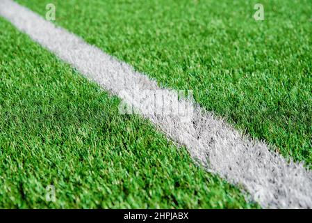 Ein Teil des Fußballfeldes aus der Nähe, künstliches grünes Gras mit weißen Randlinien, Astroturf im Stadion für Sportenspiele Stockfoto