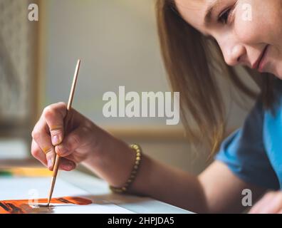 Nettes Mädchen zu Hause am Tisch zeichnet mit Farben Stockfoto