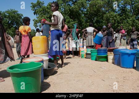 Frauen und Kinder stehen an einer Wasserpumpstation im Bangula Camp im Bezirk Nsanje, Malawi, Schlange, um Wasser zu holen. Tausende von Menschen werden im Lager zu Hause verbracht, nachdem sie vom tropischen Wirbelsturm Ana vertrieben wurden. Malawi. Stockfoto