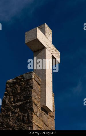 Dieses schlichte weiße Kreuz überragt ein Steindenkmal an der Stelle in Portugal, „wo das Land endet und das Meer beginnt“: Das wilde und windgepeitschte Kap Cabo da Roca, bekannt als der westlichste Punkt Kontinentaleuropas, mit seinen zerklüfteten, nahezu vertikalen Granit- und Kalksteinklippen, die etwa 42 km (26 Meilen) von Lissabon in den Atlantischen Ozean ragen. Stockfoto