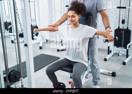 Junge Dame, die sich im Fitnessstudio einer Armrehabilitation unterzogen hat Stockfoto