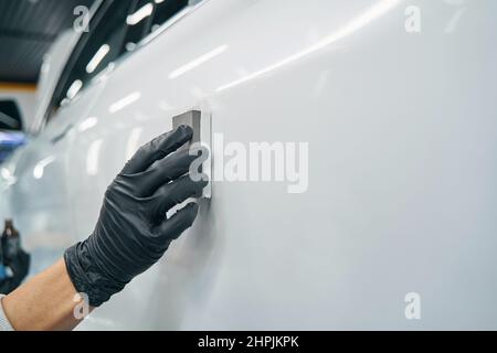 Handschuhen mit Schwabbelschwamm Block während Auto Detaillierung Stockfoto