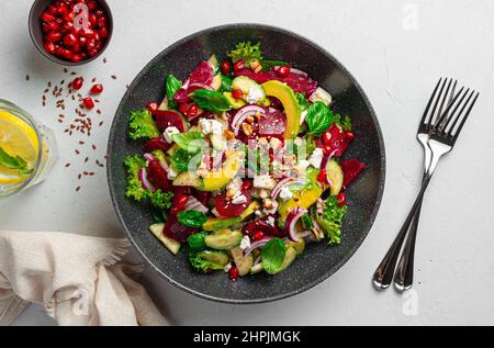 Frischer vegetarischer Salat mit Gemüse, Feta, Granatapfel und Sesam und Leinsamen. Draufsicht, Nahaufnahme. Stockfoto