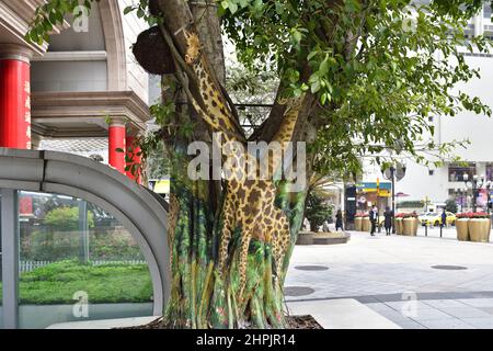 Chongqing, Chongqing, China. 22nd. Februar 2022. Am 22. Februar 2022 begann der ''Zoo'' auf dem Baum in der Jiefangbei-Fußgängerzone in Chongqing.vor kurzem, in der Jiefangbei des Yuzhong-Bezirks, Chongqing, wo beliebte Check-in-Punkte gesammelt werden, hat ein ''Zoo'' auf einem Baum begonnen, Aufmerksamkeit zu erregen. Der Reporter sah auf der Minzu Road, der Jiefangbei Fußgängerzone, dass in der Mitte der geraden Straße zwei Reihen von dichten gelben Wacholderbäumen sind. Mehr als ein Dutzend Tiere, darunter das ''Lightning''-Faultier in ''Zootopia'' und das ''Timan''-Erdmännchen in ''The Lion King''. Die Gemälde sind lebensecht und Stockfoto