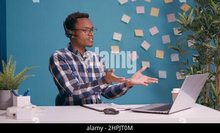 Der Callcenter-Mitarbeiter kämpft und brüllt den Kunden über die Telefonleitung an, indem er Kopfhörer mit Mikrofon verwendet. Mitarbeiter der Kundenbetreuung fühlen sich wütend und rufen die Person an, Telefonmarketing-Support-Chat. Stockfoto