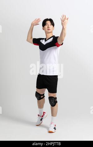 Volleyballspieler, asiatisch-koreanischer Mann, der Serve vorbereitet und den Ball serviert Stockfoto