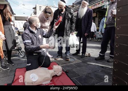 Jerusalem, Israel. 22nd. Februar 2022. Sanitäter von Magen David Adom, Israels führendem Rettungsdienst, demonstrieren und unterweisen am 22nd. Februar auf dem Shuk Mahane Yehuda Markt den Einsatz von HLW und Defibrillatoren und ihre Bedeutung für die Rettung von Menschenleben. Tausende von Defibrillatoren sind landesweit installiert und für den Einsatz an öffentlichen Orten verfügbar. Kredit: Nir Alon/Alamy Live Nachrichten Stockfoto