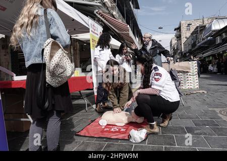 Jerusalem, Israel. 22nd. Februar 2022. Sanitäter von Magen David Adom, Israels führendem Rettungsdienst, demonstrieren und unterweisen am 22nd. Februar auf dem Shuk Mahane Yehuda Markt den Einsatz von HLW und Defibrillatoren und ihre Bedeutung für die Rettung von Menschenleben. Tausende von Defibrillatoren sind landesweit installiert und für den Einsatz an öffentlichen Orten verfügbar. Kredit: Nir Alon/Alamy Live Nachrichten Stockfoto