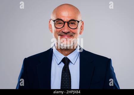 Eine kurze Aufnahme eines lächelnden Geschäftsmanns, der Anzug und Krawatte trägt, während er auf einem isolierten grauen Hintergrund steht. Speicherplatz kopieren. Stockfoto