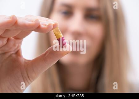 Nahaufnahme der weiblichen Hand, die bunte Pille oder Kapsel Vitaminpräparat aus der Nähe hält Stockfoto
