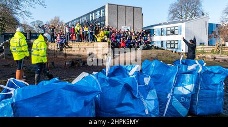 Trinity Primary School, Edinburgh, Schottland, Großbritannien, 22. Februar 2022. Botanics Topsoil for Schools: Die Ausgrabung während des Royal Botanic Garden Biomes Project führt zu einem Überschuss von 50 Tonnen Topsoil, der von der Baufirma Balfour Beatty an Schulen, Zuteilungen und Gemeindeorganisationen abgegeben wird. An der Trinity Primary School findet eine Lieferung von 5 Tonnen statt, um Boden oder Erde zu transportieren, um Pflanzgefäße im Schulgarten zu füllen, damit Schüler Gemüse anbauen können. Die Schüler der Grundschule 4 verwenden Behälter aller Formen und Größen, um die Erde zu bewegen, um die Pflanzgefäße zu füllen; Teamarbeit ist erforderlich Stockfoto