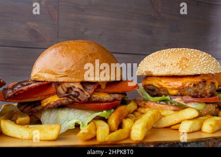 Zwei saftige Burger mit pommes frites auf einer Holzplatte und Holzbackround Stockfoto