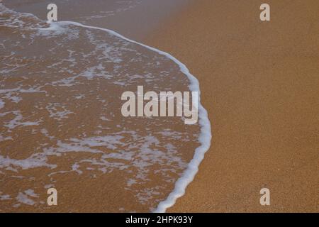 Welle und Strand. Ruhige Welle am Sandstrand. Reisehintergrundfoto. Urlaubs- oder Urlaubskonzept. Stockfoto