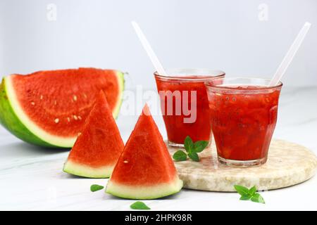 Wassermelone-Eisgetränk auf klarem Glas auf isoliertem weißem Hintergrund serviert. Selektiver Fokus mit Wassermelonen-Fruchtscheiben. Platz für Text kopieren. Stockfoto