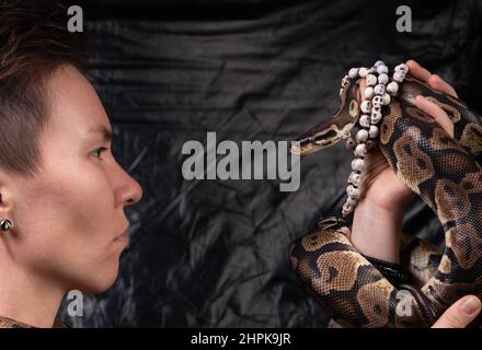 Foto einer ernsthaften Frau, die in die Augen der Schlangen schaut Stockfoto