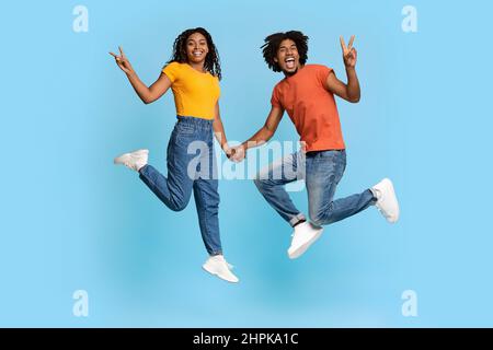 Glückliche afroamerikanische Liebhaber gestikulieren auf Blau Stockfoto