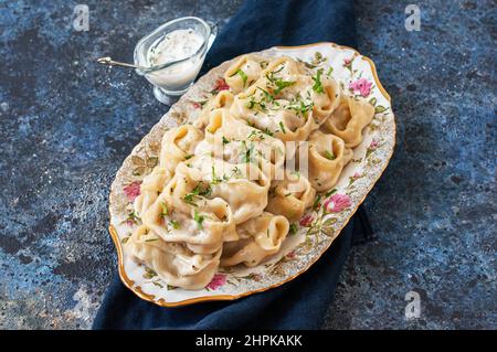 Traditionelle orientalische Küche – auf einem Teller mit Sauce auf blauem Hintergrund wird gegrilltes Rind- oder Lammfleisch serviert. Stockfoto