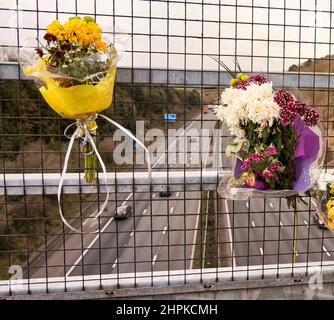 Blumensträuße, die an einer Fußgängerbrücke über die verkehrsreiche Autobahn M5 in Somerset UK befestigt sind Stockfoto