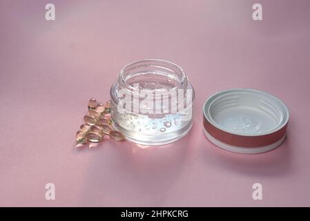 Gel mit Hyaluronsäure in einem Glas und Kapseln auf einem rosa Hintergrund Stockfoto