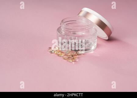 Gel mit Hyaluronsäure in einem Glas und Kapseln auf einem rosa Hintergrund Stockfoto