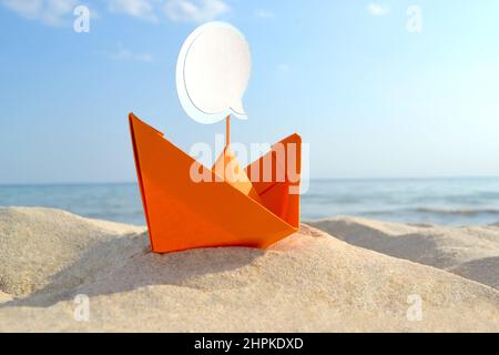 Orange Papier Boot auf Sandy Seashore Nahaufnahme kleines Boot aus Papier auf dem Hintergrund Stockfoto