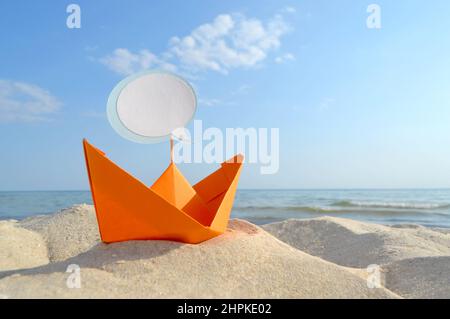 Orange Papier Boot auf Sandy Seashore Nahaufnahme kleines Boot aus Papier auf dem Hintergrund Stockfoto