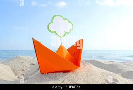 Orange Papier Boot auf Sandy Seashore Nahaufnahme kleines Boot aus Papier auf dem Hintergrund Stockfoto