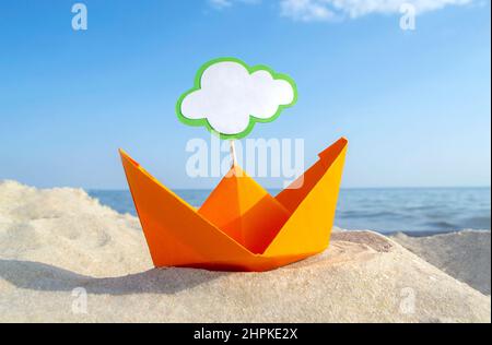Orange Papier Boot auf Sandy Seashore Nahaufnahme kleines Boot aus Papier auf dem Hintergrund Stockfoto