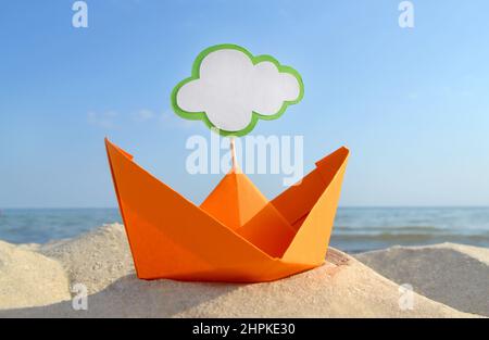 Orange Papier Boot auf Sandy Seashore Nahaufnahme kleines Boot aus Papier auf dem Hintergrund Stockfoto