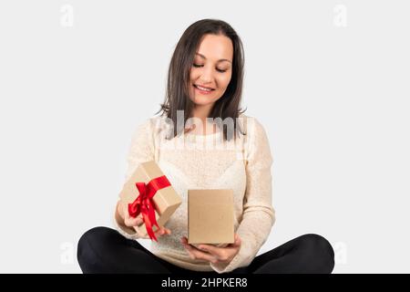 Die junge Frau erhielt eine Geschenkbox für einen besonderen Tag und öffnete sie mit einem glücklichen Gesicht. Hochwertige Fotos Stockfoto