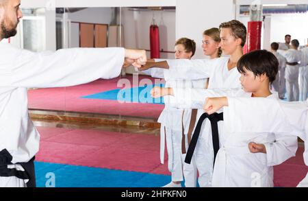 Kinder trainieren Karate-Bewegungen mit Trainer Stockfoto